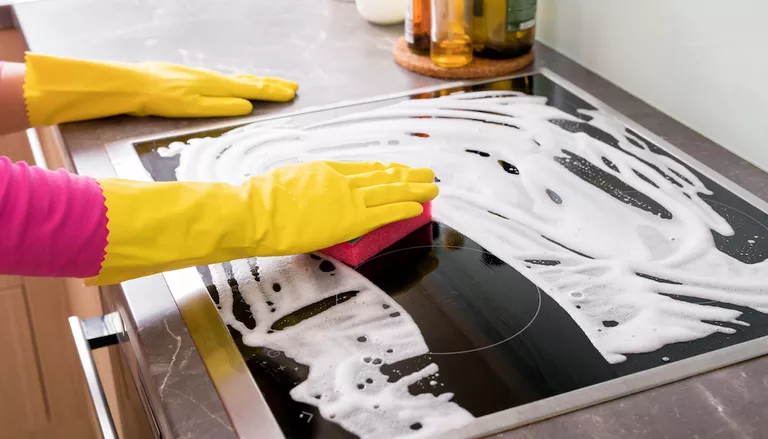 person cleaning a glass ceramic stove top or cooktop