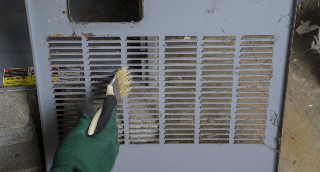 HVAC technician cleaning dirty furnace