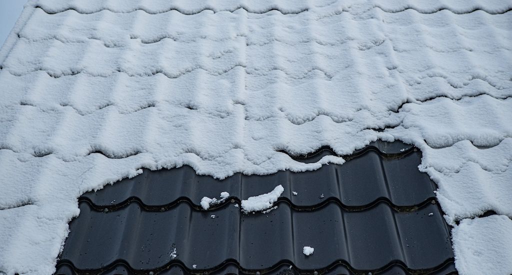 bare spot on snow covered tile roof