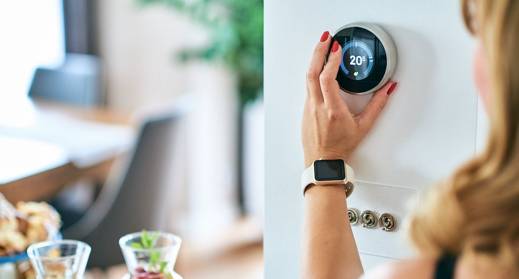 woman turning on thermostat
