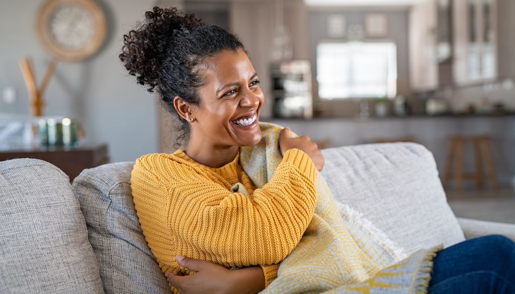 woman wrapping herself in blanket on couch