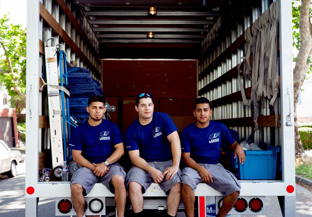Three men in matching shirts sitting inside a moving van