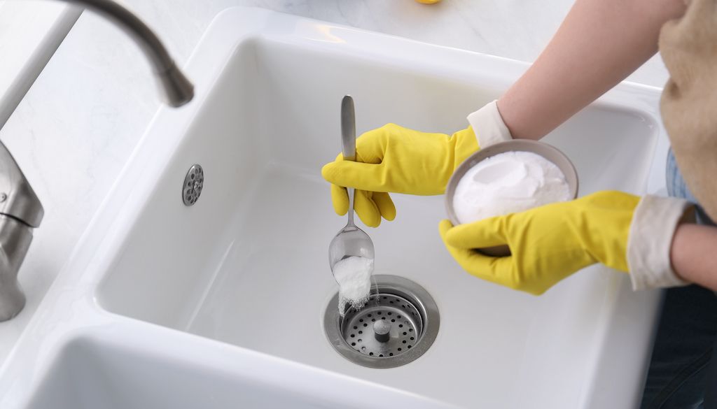 pouring baking soda in sink to clean drain or garbage disposal