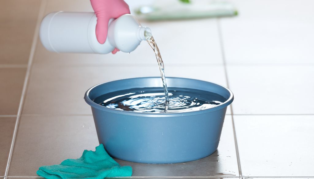 pouring bleach into bucket for floor cleaning