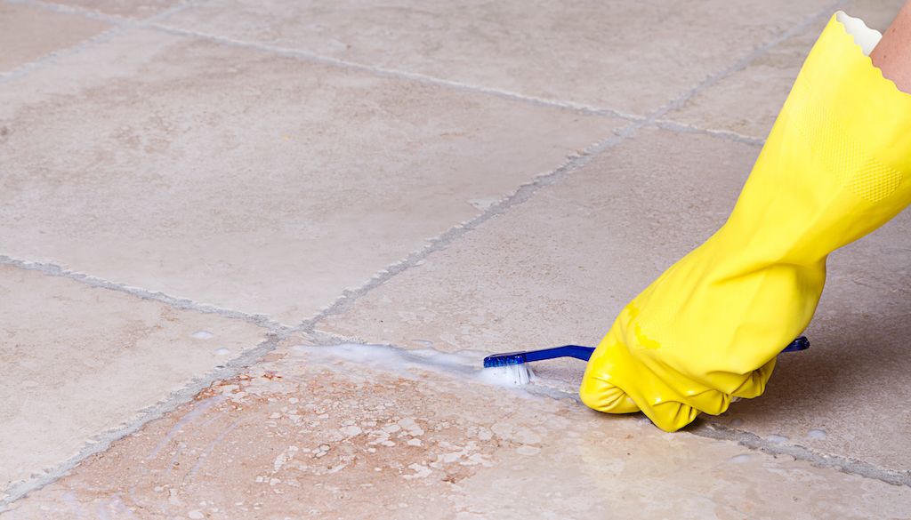 rubber glove using toothbrush to clean tile and grout