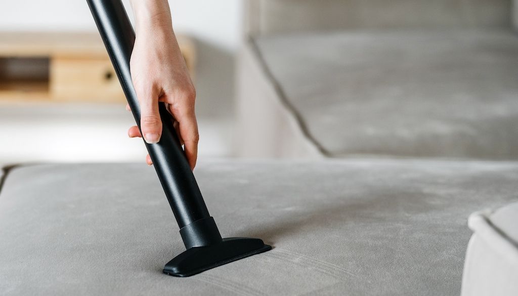 vacuum with hose being used on couch