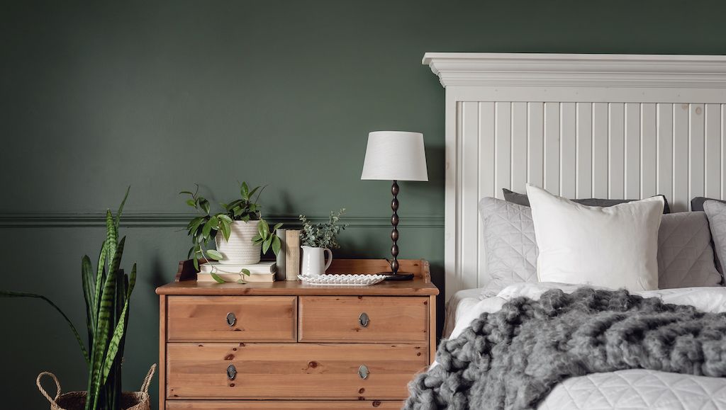 bedroom with deep, dark green wall behind headboard