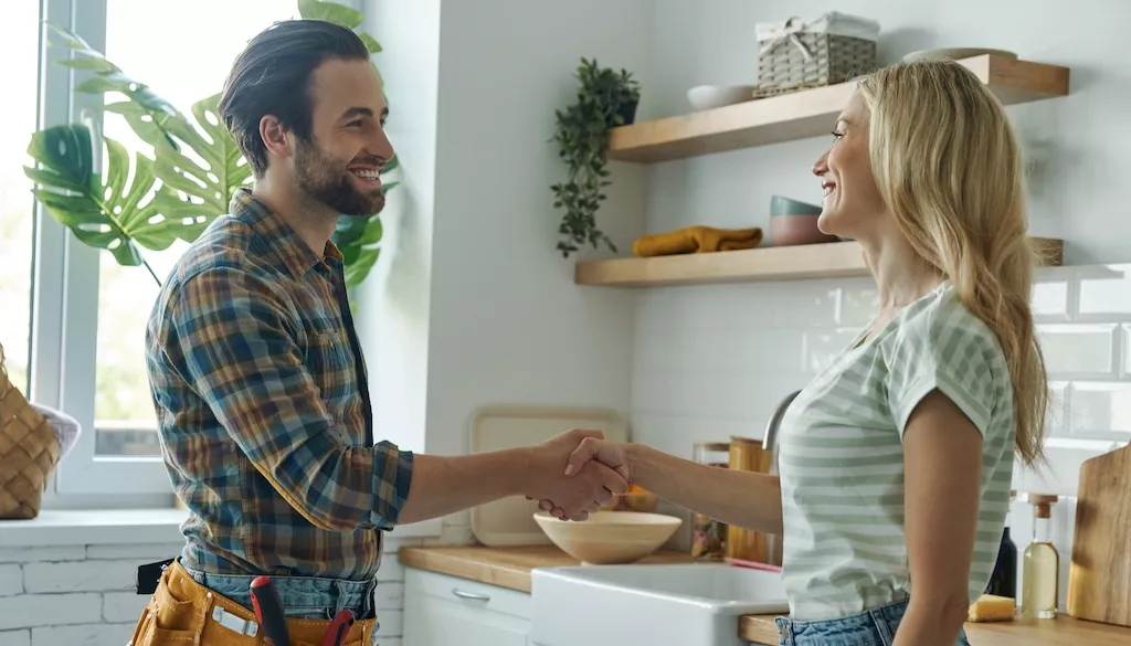 woman shaking hands with plumber