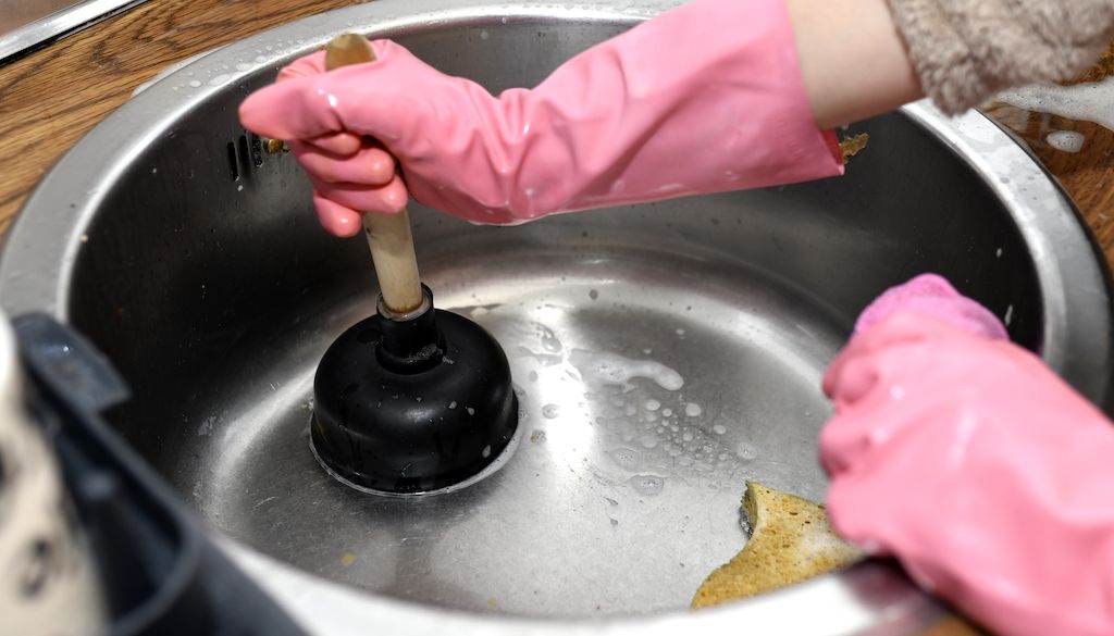 person using a cup plunger to unclog sink