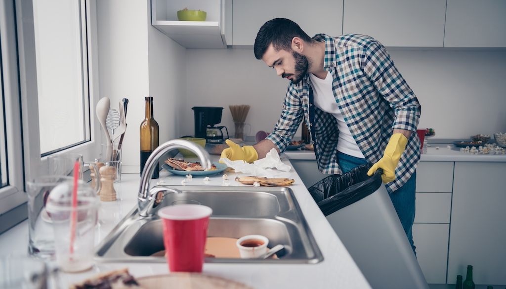 man cleaning up dirty kitchen