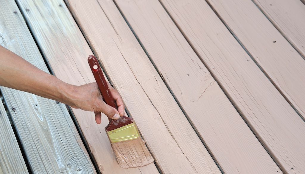 hand using brush to paint composite wood decking