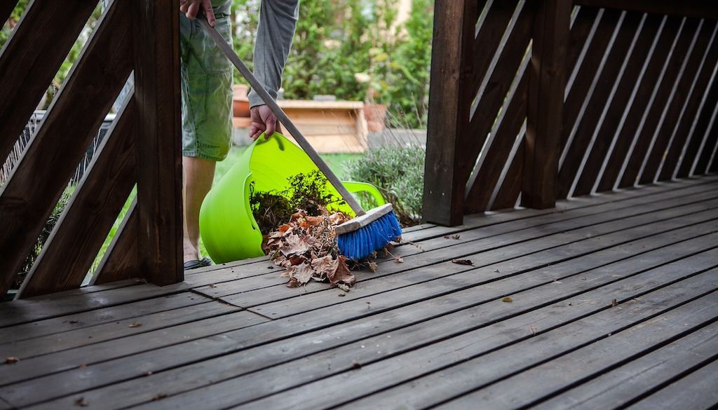 person sweeping leaves and debris off deck