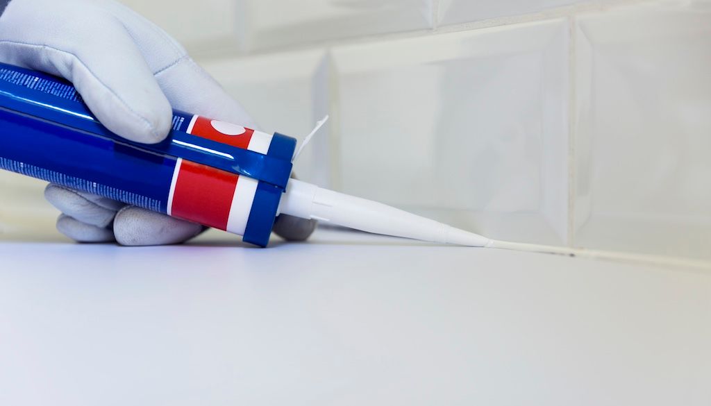 plumber applying silicone to sink