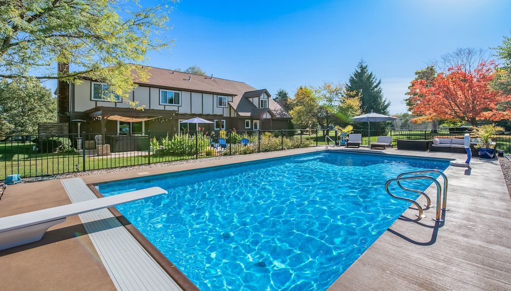 backyard swimming pool remodel with fence and diving board