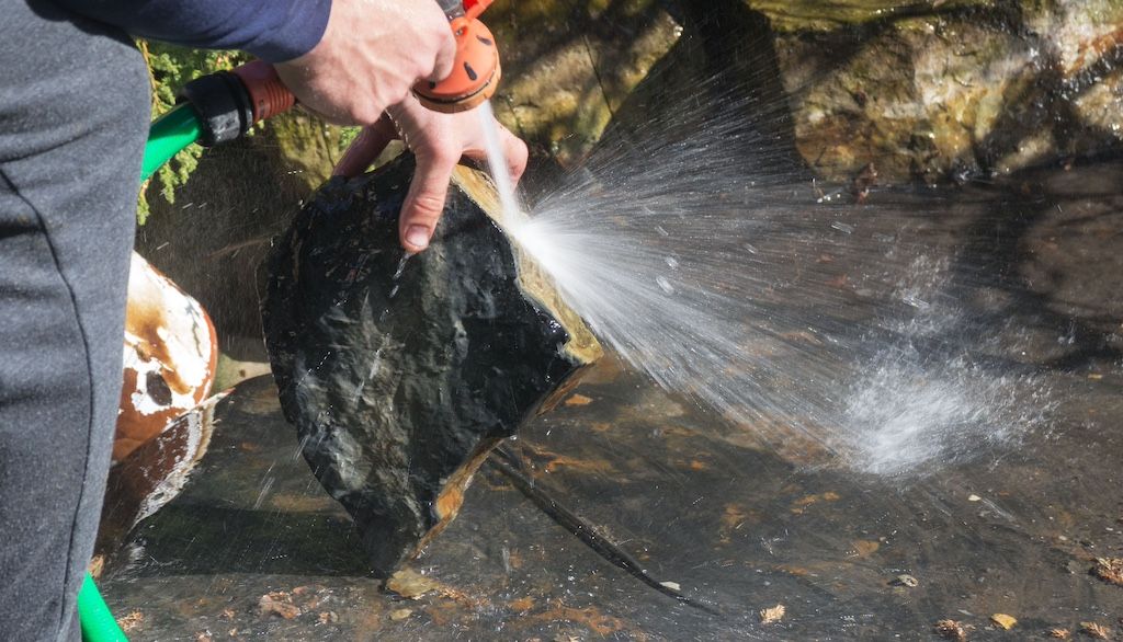 worker washing landscape rocks in water feature