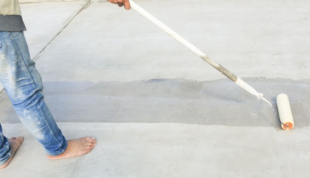 person painting a concrete porch