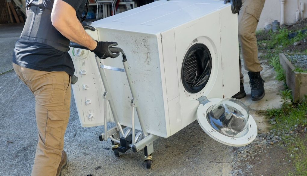 junk removal pros carrying a washer/dryer
