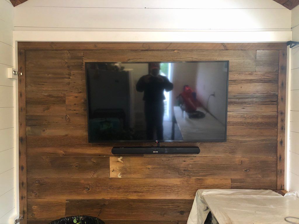Reclaimed wood swinging barn door with mounted TV
