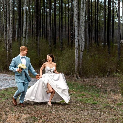 Bride and Groom run hand in hand down tree lined p