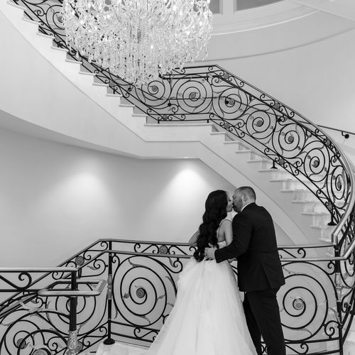 Bride and Groom kiss while standing under chandeli