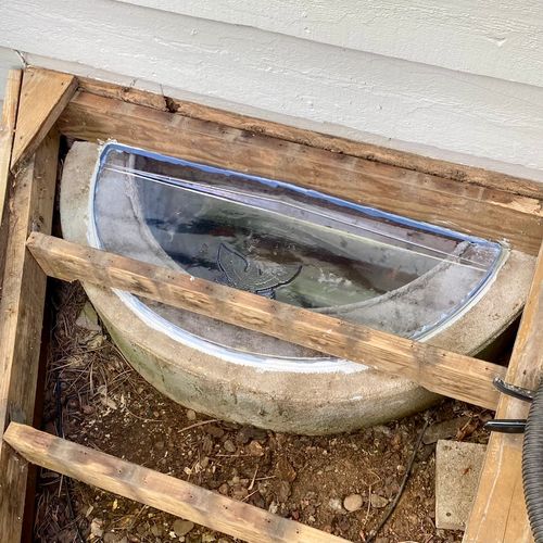 Window well cover installed under existing deck to