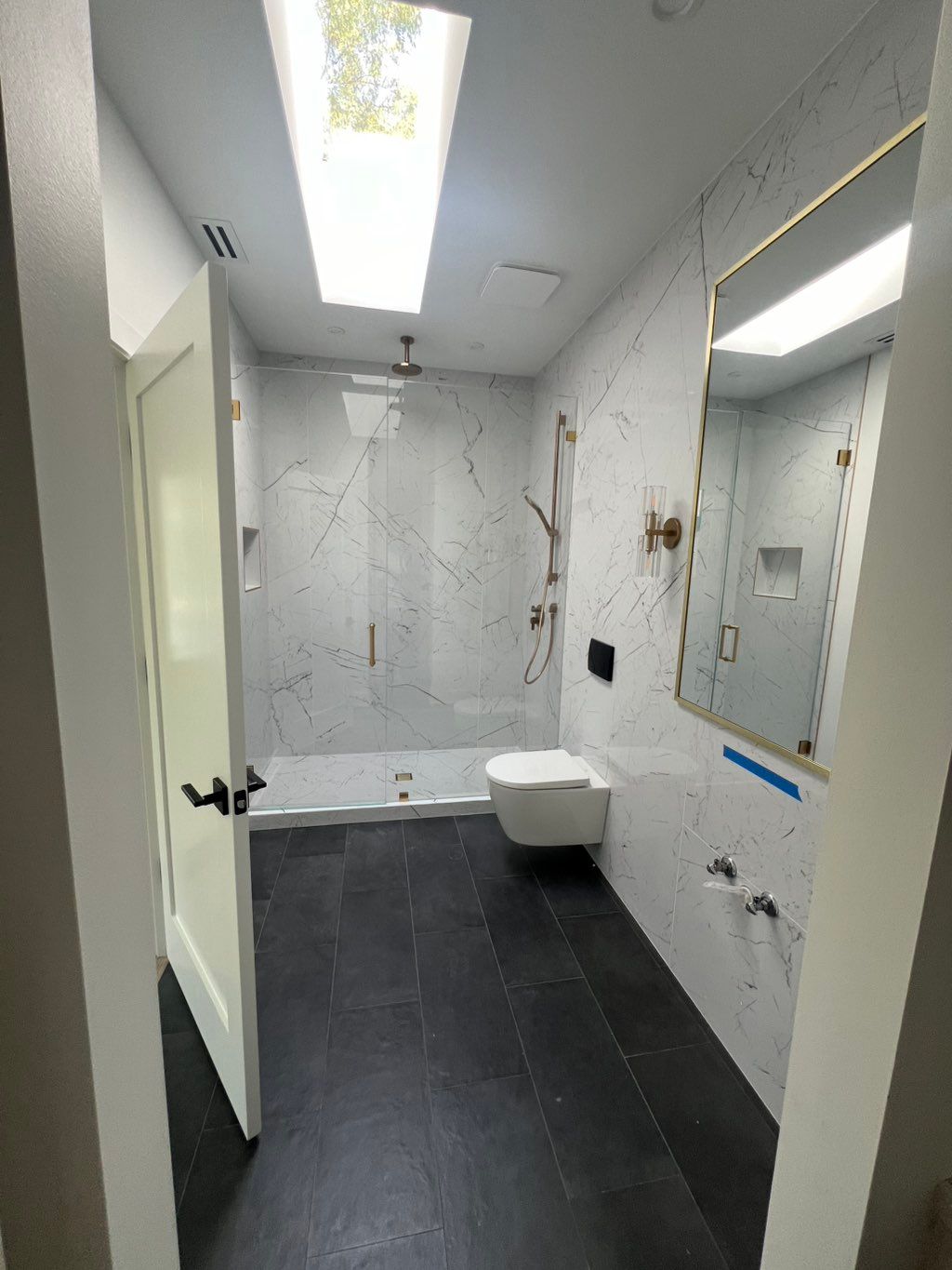 Bathroom tile, toilet and gold fixtures.