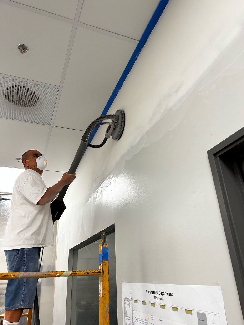 Sanding in office space using electrical sander. 